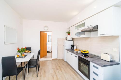 a kitchen with white cabinets and a table and chairs at Apartments Blažević in Mlini
