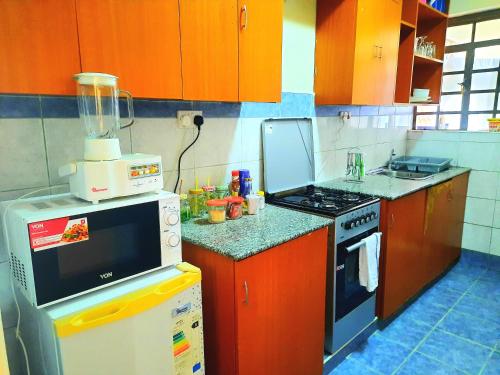 a small kitchen with orange cabinets and a stove at Cozy Nest-2 Bedroomed Apartment WiFi ,Netflix close to JKIA in Syokimau