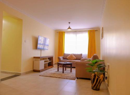 a living room with a couch and a tv at Lux Suites Greatwall Gardens Apartments in Machakos