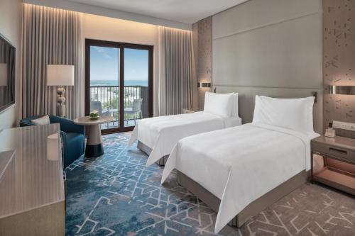 Palace Beach Resort Fujairah في الفجيرة: غرفة فندقية بسريرين وبلكونة