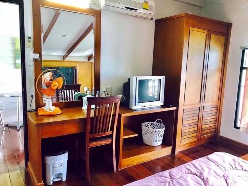 a bedroom with a desk with a tv on it at Koi Seahouse in Ko Chang