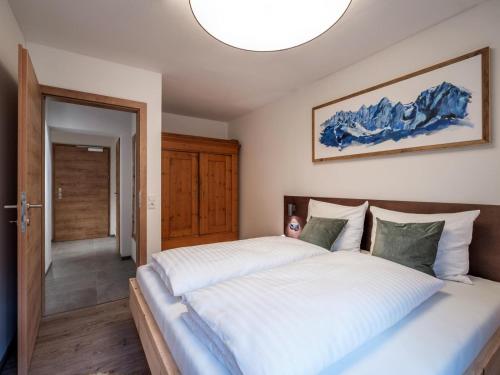 a bedroom with a large white bed with a chandelier at Alpine Homes - Hopfgarten in Hopfgarten im Brixental