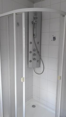 Baño blanco con ducha con puerta de cristal en Ferienwohnung auf dem Pferdehof, en Schotten