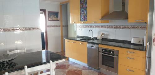 a kitchen with yellow cabinets and black counter tops at Apartamento Céntrico con Parking in Santander