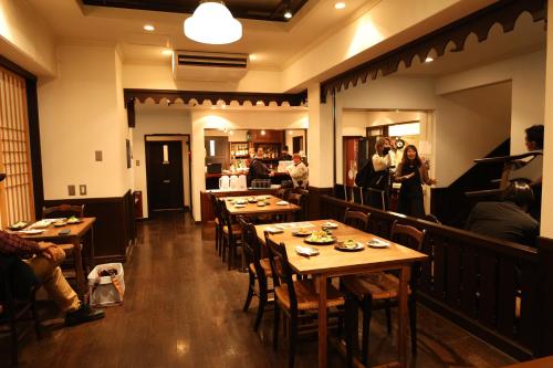 een restaurant met houten tafels en mensen in een kamer bij Guest House Ichiyama Shukuba in Matsumoto