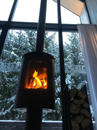 a fireplace in front of a window with snow at Czarne Domki in Zwierzyniec