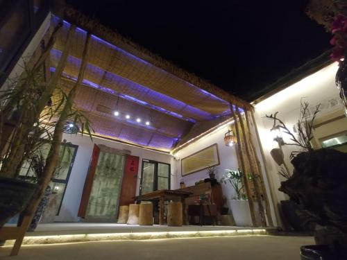a house with a lit up porch at night at Waiting for the Blossoms B&B Tea House in Shantou