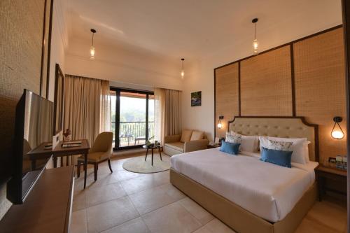 a hotel room with a bed and a desk and a television at Bhanu The Fern Forest Resort & Spa, Jambughoda in Jambughoda