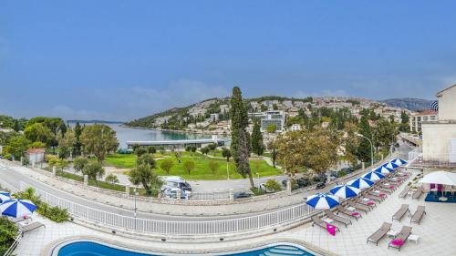 um resort com piscina, cadeiras e guarda-sóis em Hotel Komodor em Dubrovnik