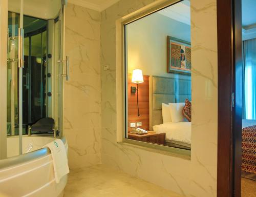 a bathroom with a tub and a sink and a mirror at Swiss Inn Nexus Hotel in Addis Ababa