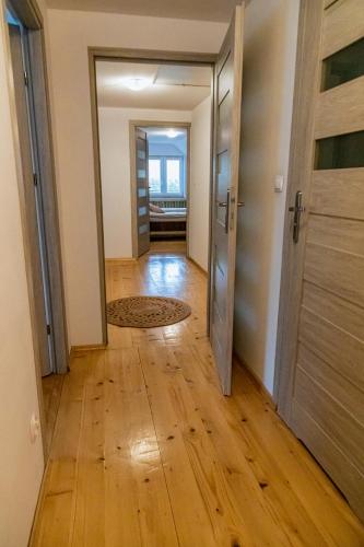 an empty hallway with a wooden floor and an open door at Beskidzki Klimat Jaśliska in Jaśliska