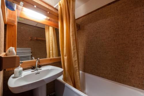 uma casa de banho com um lavatório, um espelho e uma banheira em Equiria - 1 chambre - balcon em Saint-Léger-les-Mélèzes