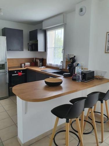 une cuisine avec une table et deux tabourets de bar dans l'établissement Maison calme,prêt de la mer, à Bernières-sur-Mer