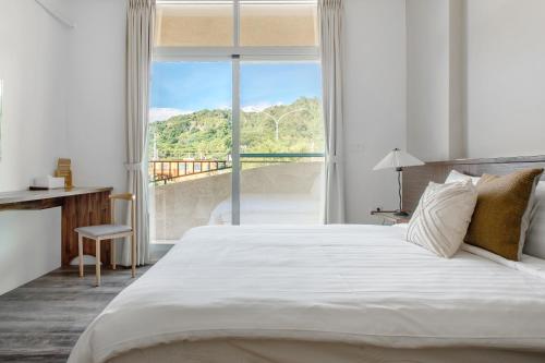 1 dormitorio con cama grande y ventana grande en H& Yu Krung Style Inn en Taitung