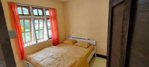 Cama pequeña en habitación con 2 ventanas en Cenggo Homestay en Ruteng