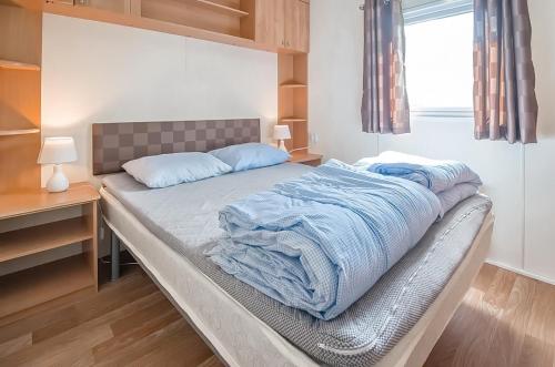 Una cama en un dormitorio con mantas azules. en KustCamp Gamleby en Gamleby