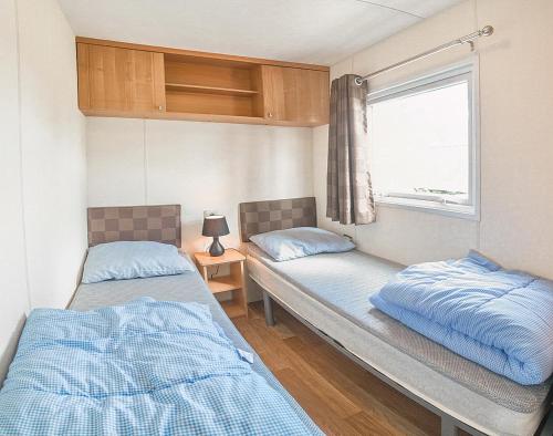 2 Betten in einem kleinen Zimmer mit Fenster in der Unterkunft KustCamp Gamleby in Gamleby