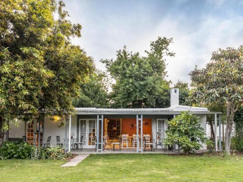a white house with a porch and trees at Greyton Lodge in Greyton