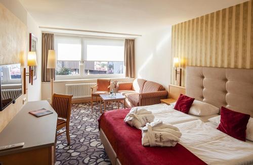 a hotel room with a bed and a living room at Berghotel Bastei in Lohmen