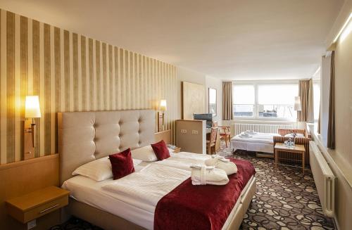 a hotel room with a large bed with red pillows at Berghotel Bastei in Lohmen
