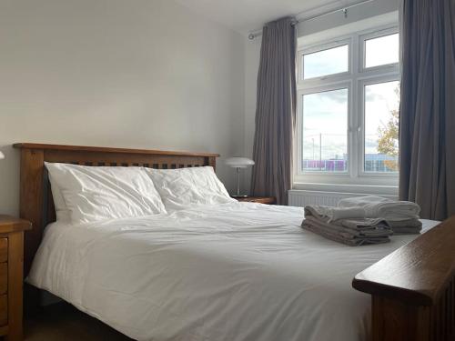 a bedroom with a white bed with a window at Family friendly new flat at London Gants Hill Station near Ilford in Wanstead