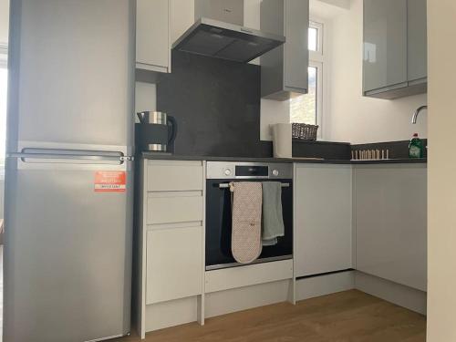 a kitchen with a stove and a refrigerator at Family friendly new flat at London Gants Hill Station near Ilford in Wanstead