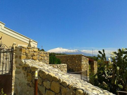a building with a stone wall with a mountain in the background at Vecchia Dimora Resort in Centuripe
