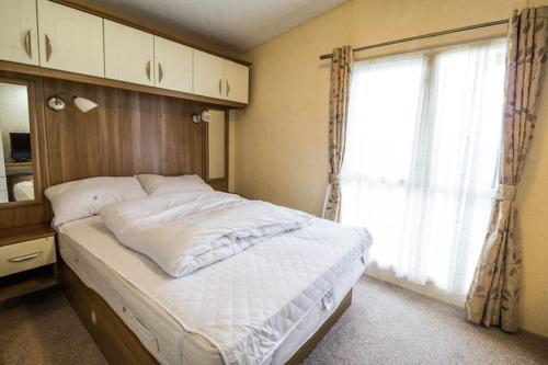 a bedroom with a large bed with a window at Sunset Drive - Luxury caravan in Great Yarmouth