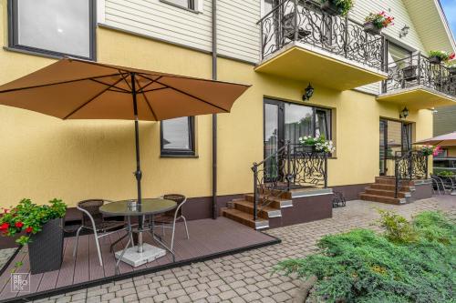 a patio with a table and an umbrella in front of a building at Senoji Palanga in Palanga