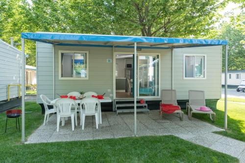 a tiny house with a blue roof and a table and chairs at San Francesco Camping Village in Desenzano del Garda