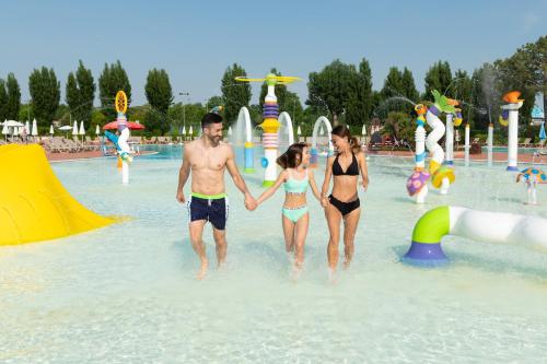 a group of three people walking in the water at a water park at San Francesco Camping Village in Desenzano del Garda