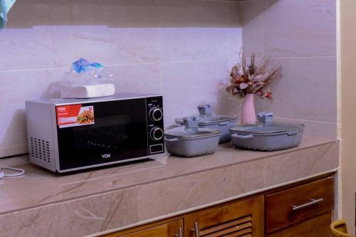 a counter with three pots and a microwave on it at Lovely and homely 2 bedroom Serviced Apartment in Kilifi