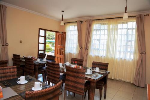 a dining room with tables and chairs and windows at Davis Court in Nyeri