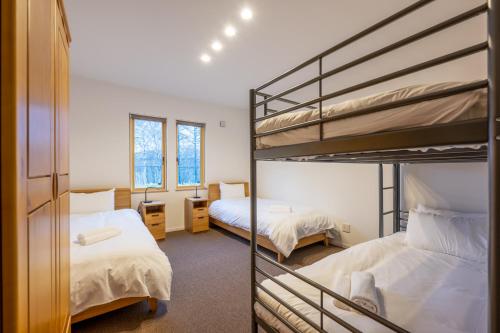 a bedroom with two bunk beds and a mirror at RuPow Lodge - walking distance to Rusutsu Resort in Rusutsu