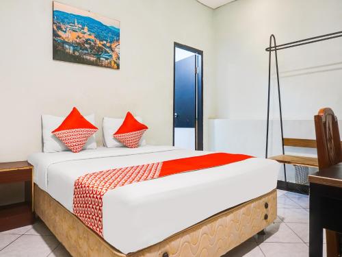 1 dormitorio con 1 cama grande con almohadas rojas en OYO 3131 Sayang Home Stay en Makassar