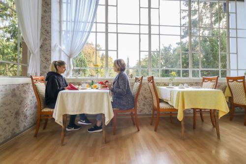 two women sitting at tables in a restaurant at Kurvilla am Park in Bad Kissingen