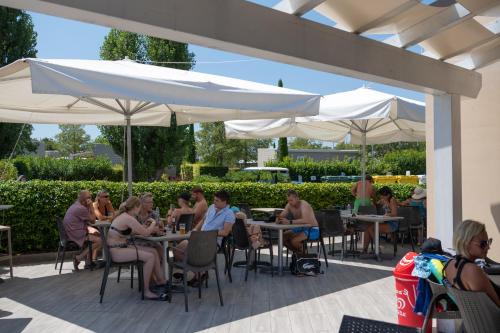 a group of people sitting at tables under umbrellas at San Francesco Camping Village in Desenzano del Garda