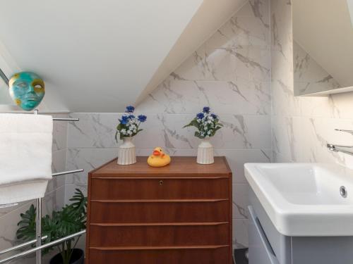 a bathroom with a sink and a wooden cabinet with flowers at Radiant Penthouse on the Banks of the Thames in Windsor