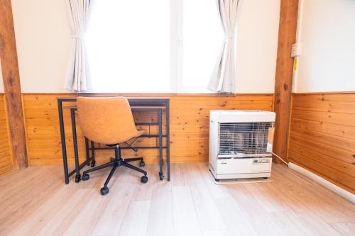a desk with a chair and a heater in a room at Woodhouse Yasunaya in Lake Toya