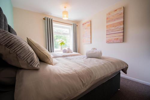 ein großes Bett in einem Zimmer mit Fenster in der Unterkunft 3-bedroom house with garden, conservatory, in centre of Worcester in Worcester