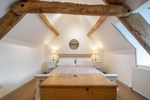 um quarto com uma cama grande e uma mesa de madeira em Park Cottage em Minchinhampton