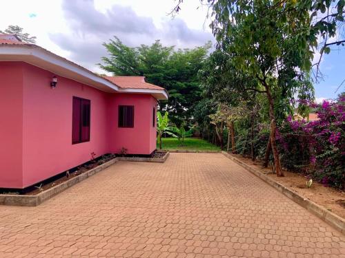una casa rosa su una strada di mattoni con alberi di Bungalow x Garten & Terrasse x WLAN x europäisch a Moshi