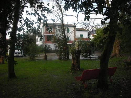 a red bench in a park with a building in the background at B&B Da Pio in Pietrasanta