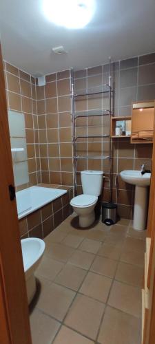 a bathroom with two toilets and a tub and two sinks at Apartamentos Boabdil in Sierra Nevada