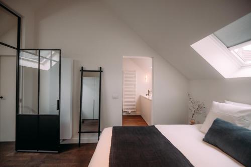 ein weißes Schlafzimmer mit einem Bett und einem Dachfenster in der Unterkunft Sud d'Anvers in Antwerpen