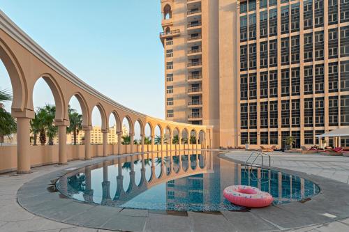 uma ponte sobre uma piscina numa cidade com edifícios em Al Gassar Resort em Doha