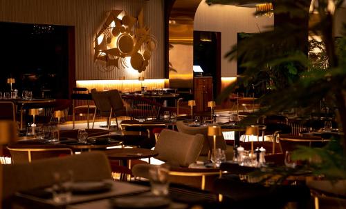 a restaurant with tables and chairs and a chandelier at Al Gassar Resort in Doha