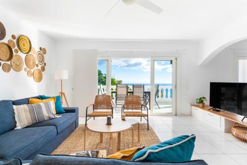 uma sala de estar com um sofá azul e cadeiras em Villa Verode - Private Heated Saltwater Pool em Tabaiba