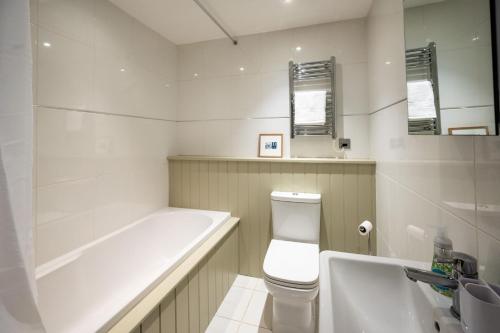 a bathroom with a tub and a toilet and a sink at Lily Cottage in Little Walsingham