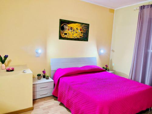 - une chambre avec un lit doté d'un couvre-lit rose dans l'établissement Pietre Nere House, à Pozzallo